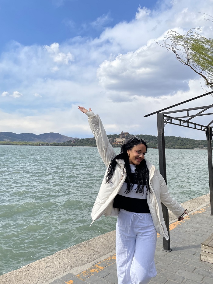 A female CET study abroad student posing with her arms spread out near the Summer Palace