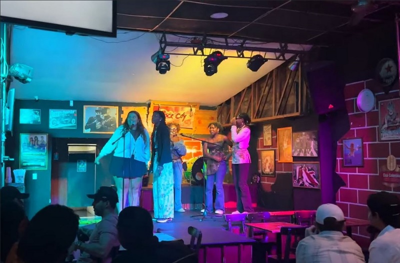 A group of study abroad students standing by mics and singing at a karaoke bar