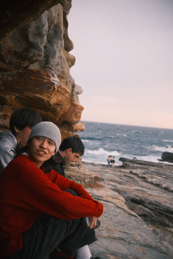 Three guys sitting on the rocks while watching a sunset by the beach in Wakayama
