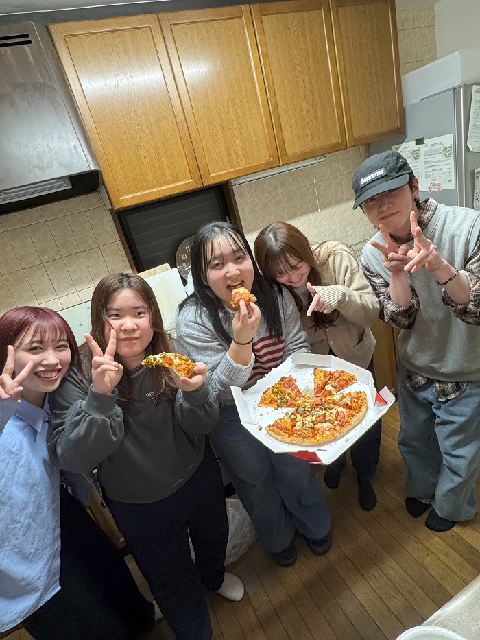 A group of CET Japan students and roommates while they eat a slice of pizza