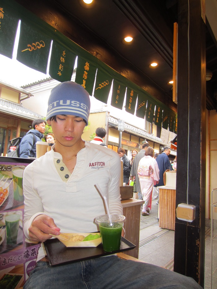 A CET Japan student looking down at his matcha drink and snack while sitting at a table in a café