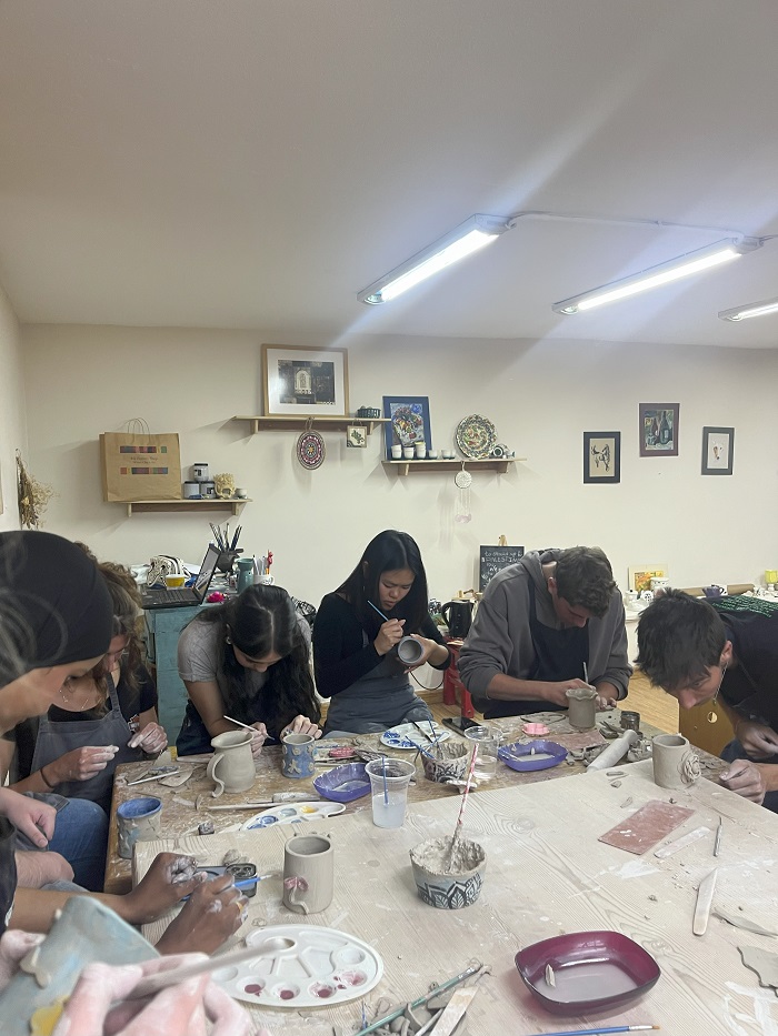 A group of CET Jordan students painting ceramics mugs around a table