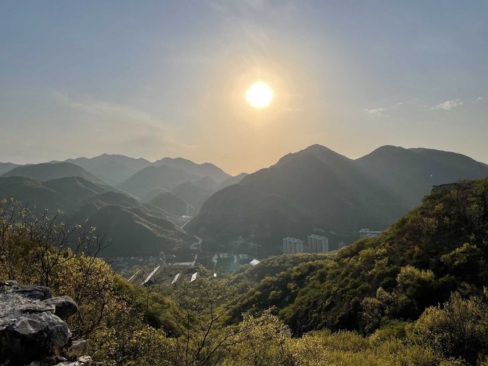 The sun shining above green mountains