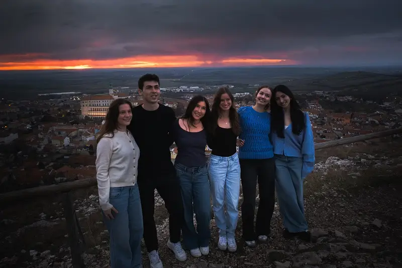 A group of CET Prague students lined up near the castle of Mikulov with the sunset and town views in the back