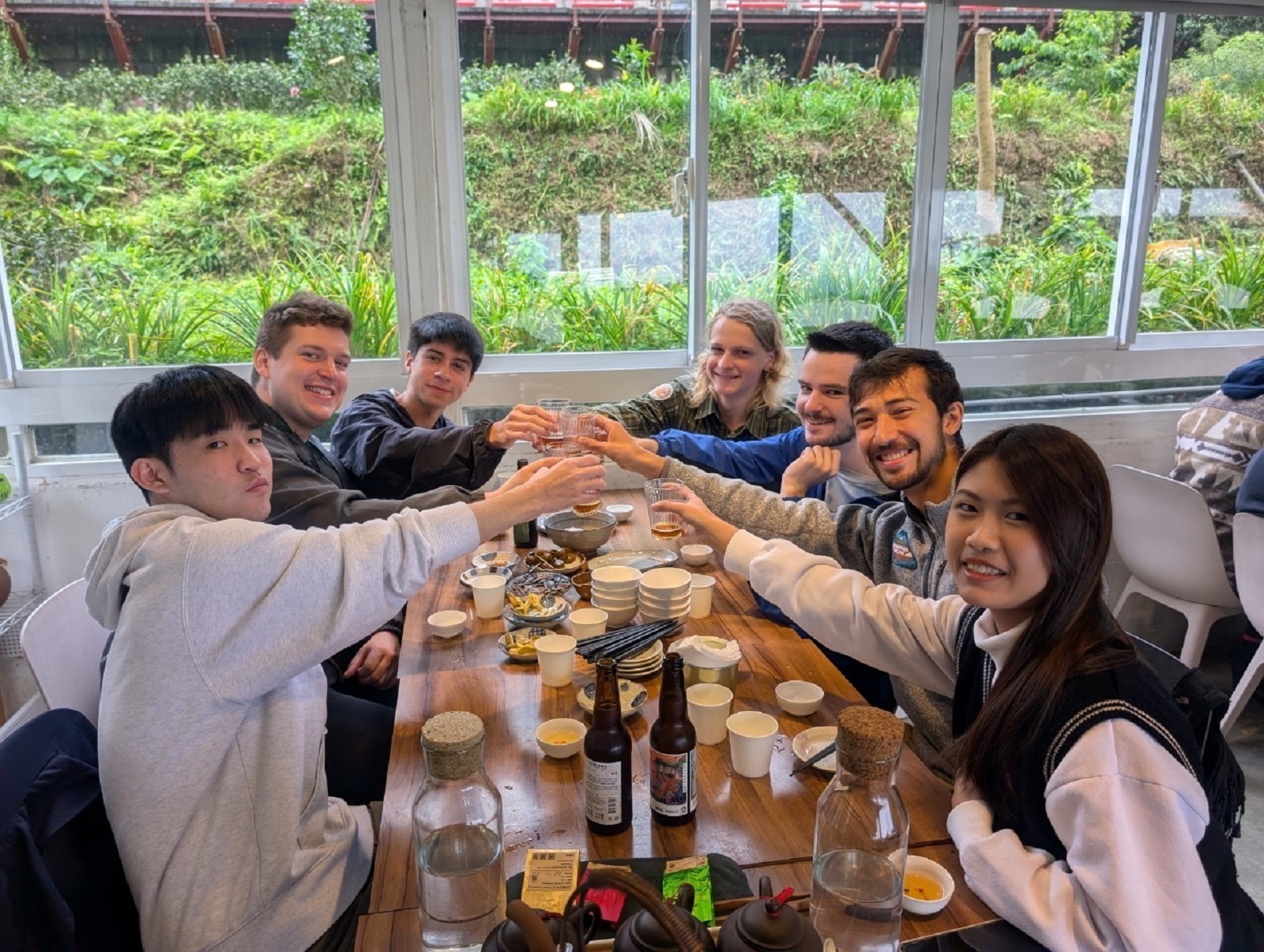 A group of CET Taiwan students and language partners cheering over a table full of drinks and food