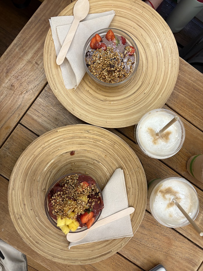 Two acai bowls with coffee drinks on a wooden table