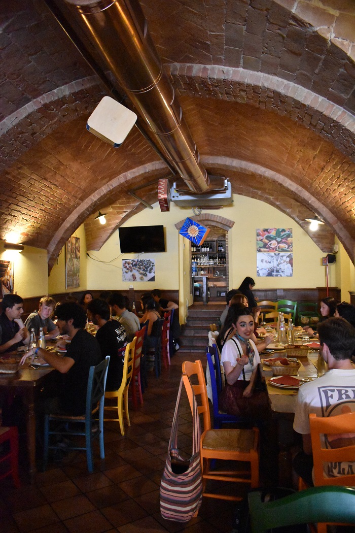 The interior of a restaurant with a rounded roof filled with people sitting at tables and eating in Siena, Italy