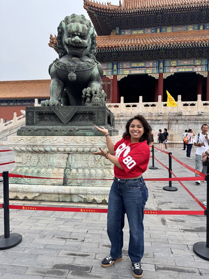 A CET Beijing student posing in front of one of the lions that guard the entrances to the palaces of the Forbidden City