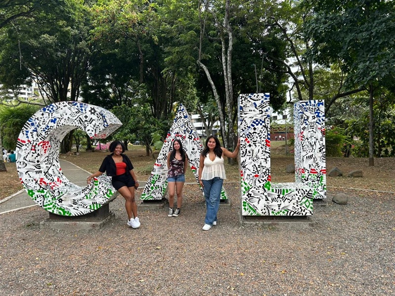 Three female CET Colombia students standing by giant letters that spell out "CALI" in Colombia