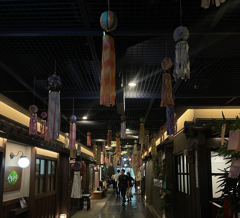People walking under the many tanabata decorations hanging up in the Umeda Sky Building in Japan