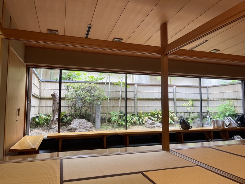 A tea ceremony room with a large window of shrubs and plants