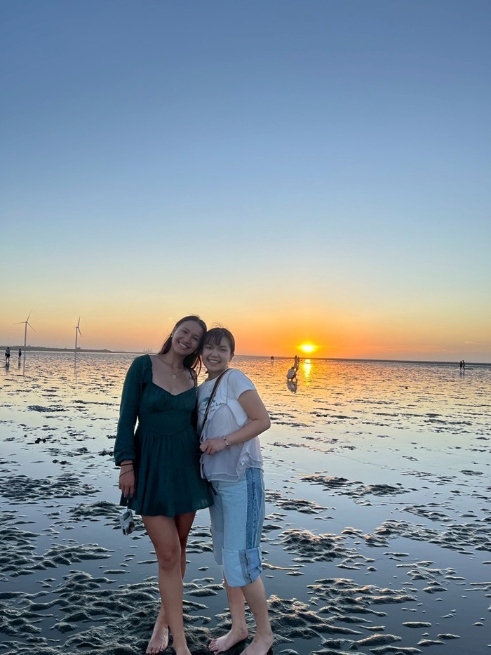 A female CET Taiwan student and her local language partner standing by the water at a beach during sunset