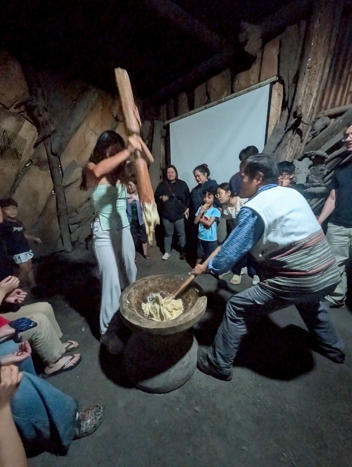 A CET Taiwan holding up a giant stick while smashing mochi in a large bowl