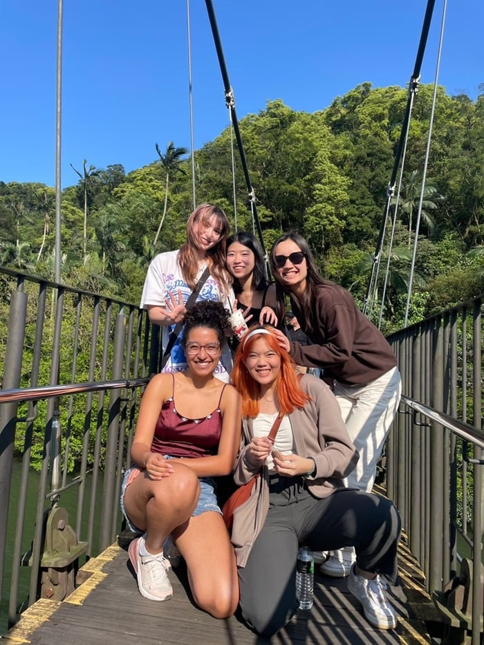 A group of five females smiling while in the middle of crossing a bridge in Yilan