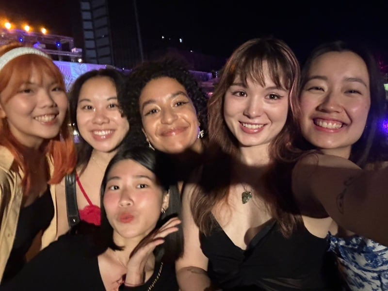 A group of females taking a selfie and smiling while it is dark outside