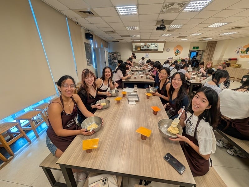 A group of students sitting around a rectangular table during a pineapple cakes-making class