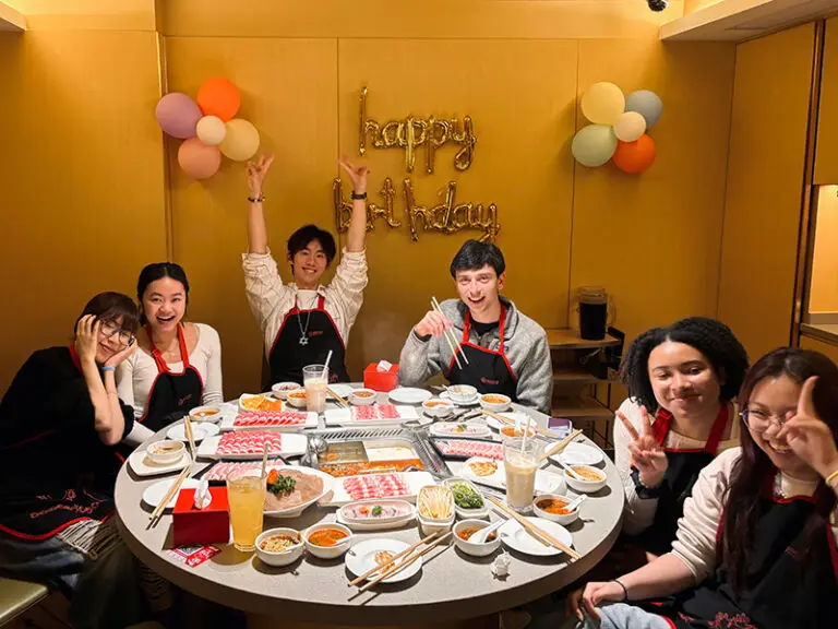 students celebrating birthday around dinner table covered in food