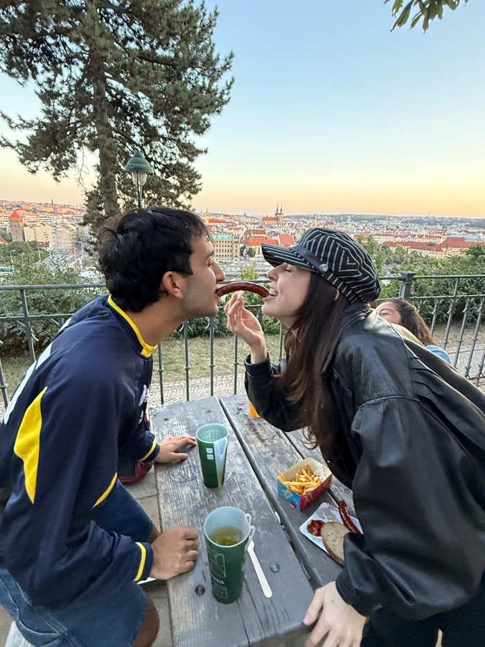 A CET Prague student and a local roommate sharing a sausage in their mouth while sitting outside at Letna beer garden in Prague
