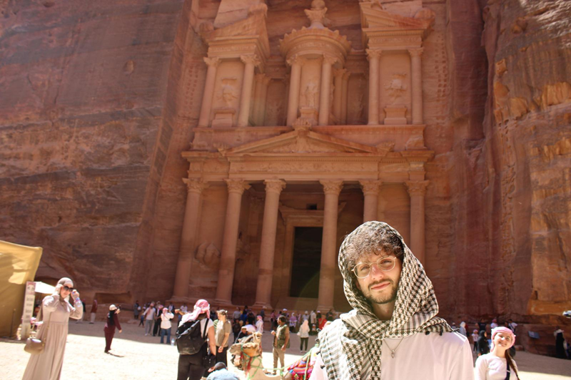 A CET Jordan student wearing a head scarf and posing by the Petra treasury in Jordan among other visitors