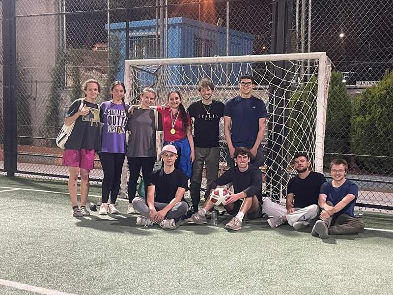 A group of CET Jordan students and their Jordanian neighbors posing by a soccer net during the evening