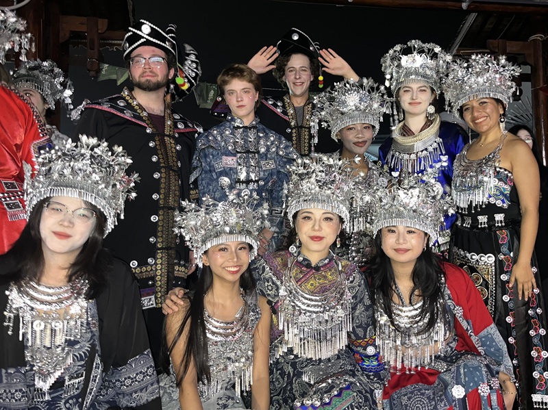 A group of CET Shanghai students and others posing while wearing traditional Miao dresses