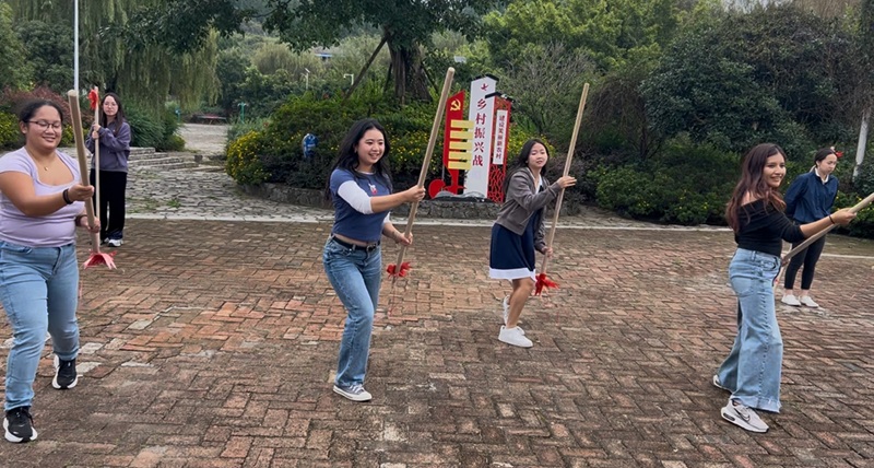 A group of CET Shanghai students standing staggered outside while holding large sticks