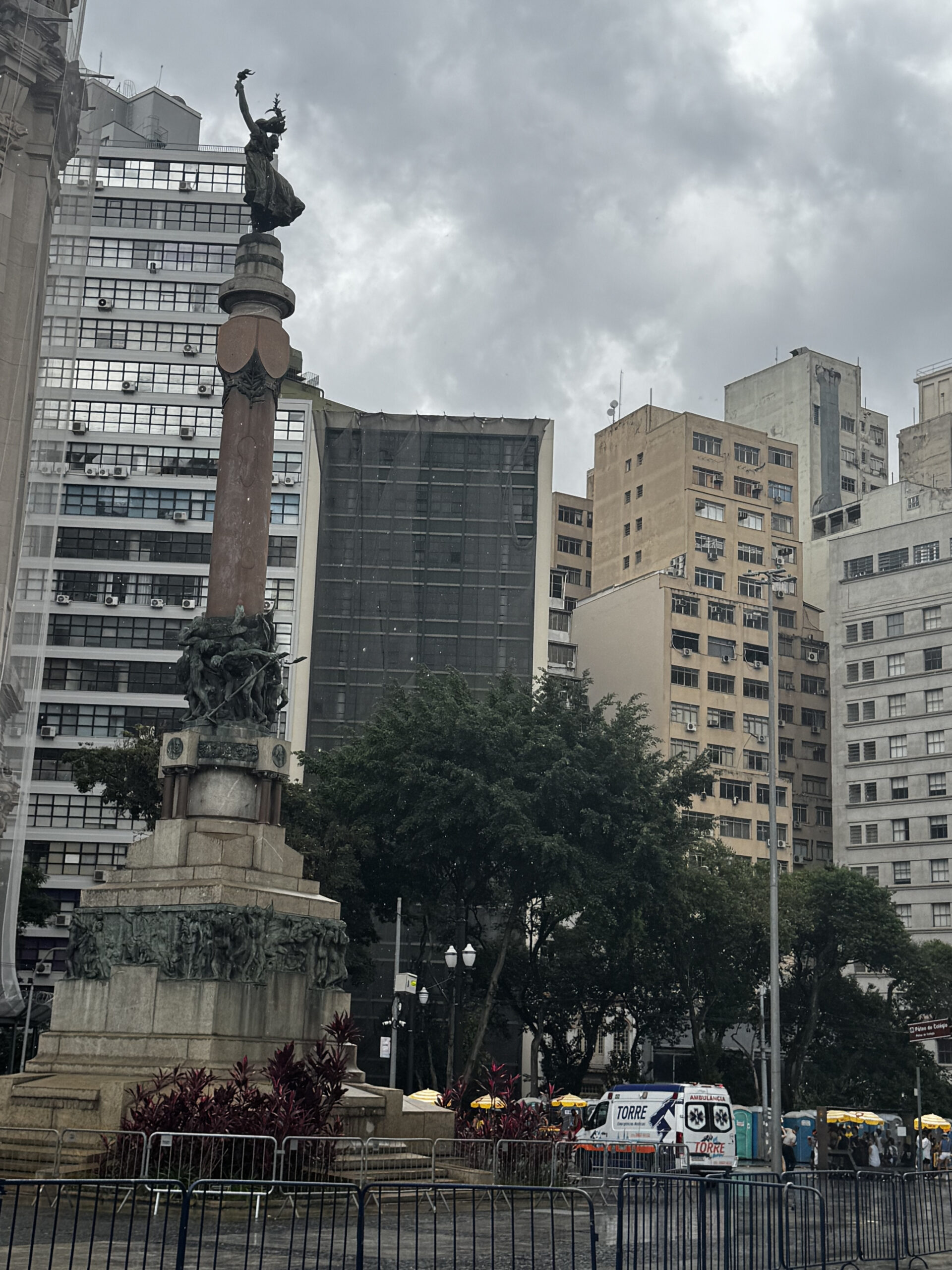 A monument standing among tall buildings in Brazil with the bottom tier of this monument symbolizing the start of the city and the middle depicting coffee workers