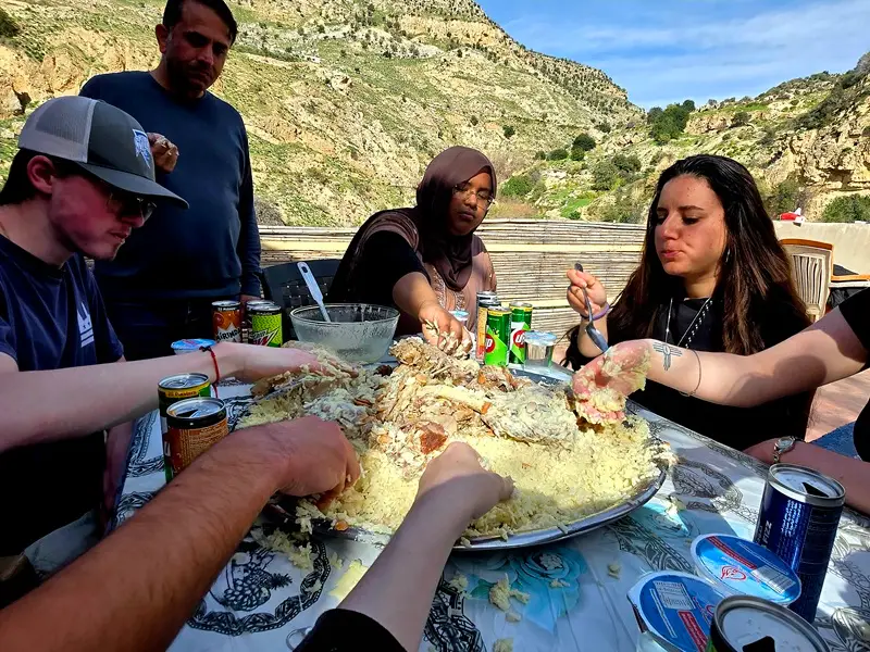 CET Jordan students sitting around a table and eating mansaf with their hands outside