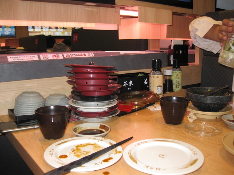 Empty sushi plates, water cups, and soy sauce dishes at a restaurant