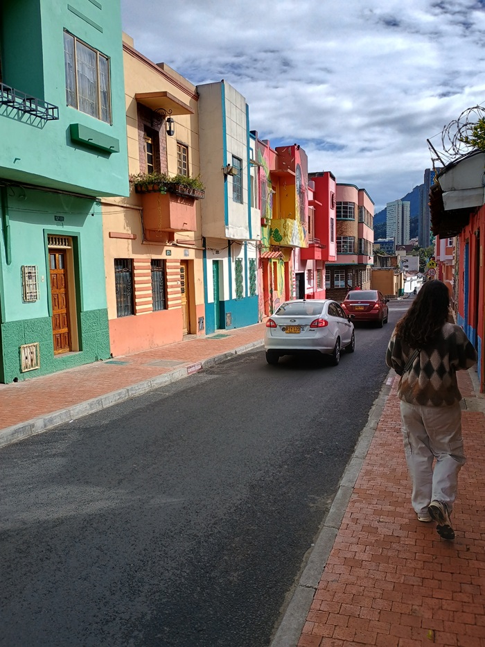 A person walking down a street of colorful buildings in Bogotá, Colombia