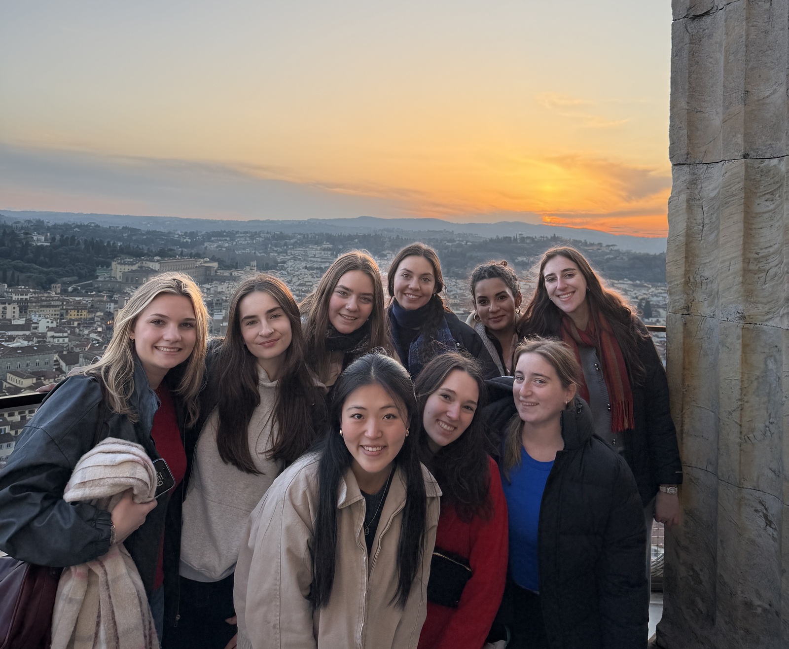A group of CET Florence students smiling while there's overlook of the city and a sunset