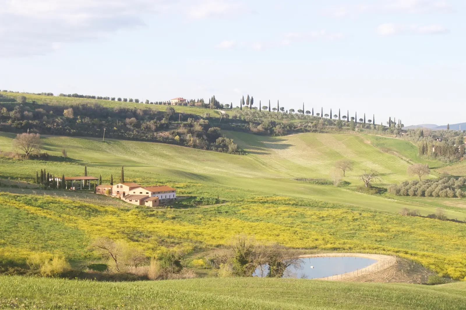 Rolling Tuscan hills of Pienza with small house and a pond 