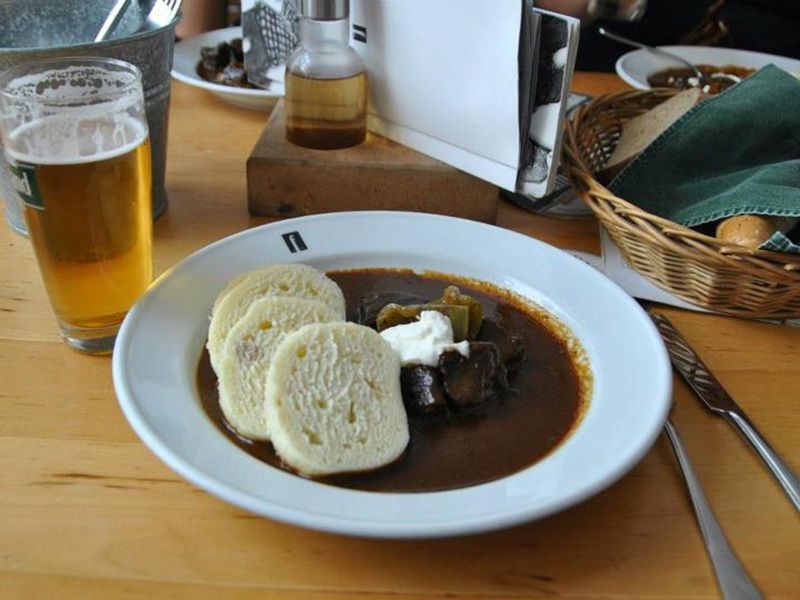 A plate of a traditional Czech goulash served with bread dumplings and dark gravy