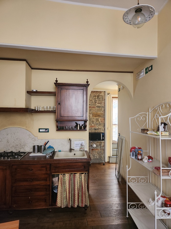 Dark stained wooden wall cabinet features two doors and a lower shelf for storage inside an apartment in Florence, Italy.