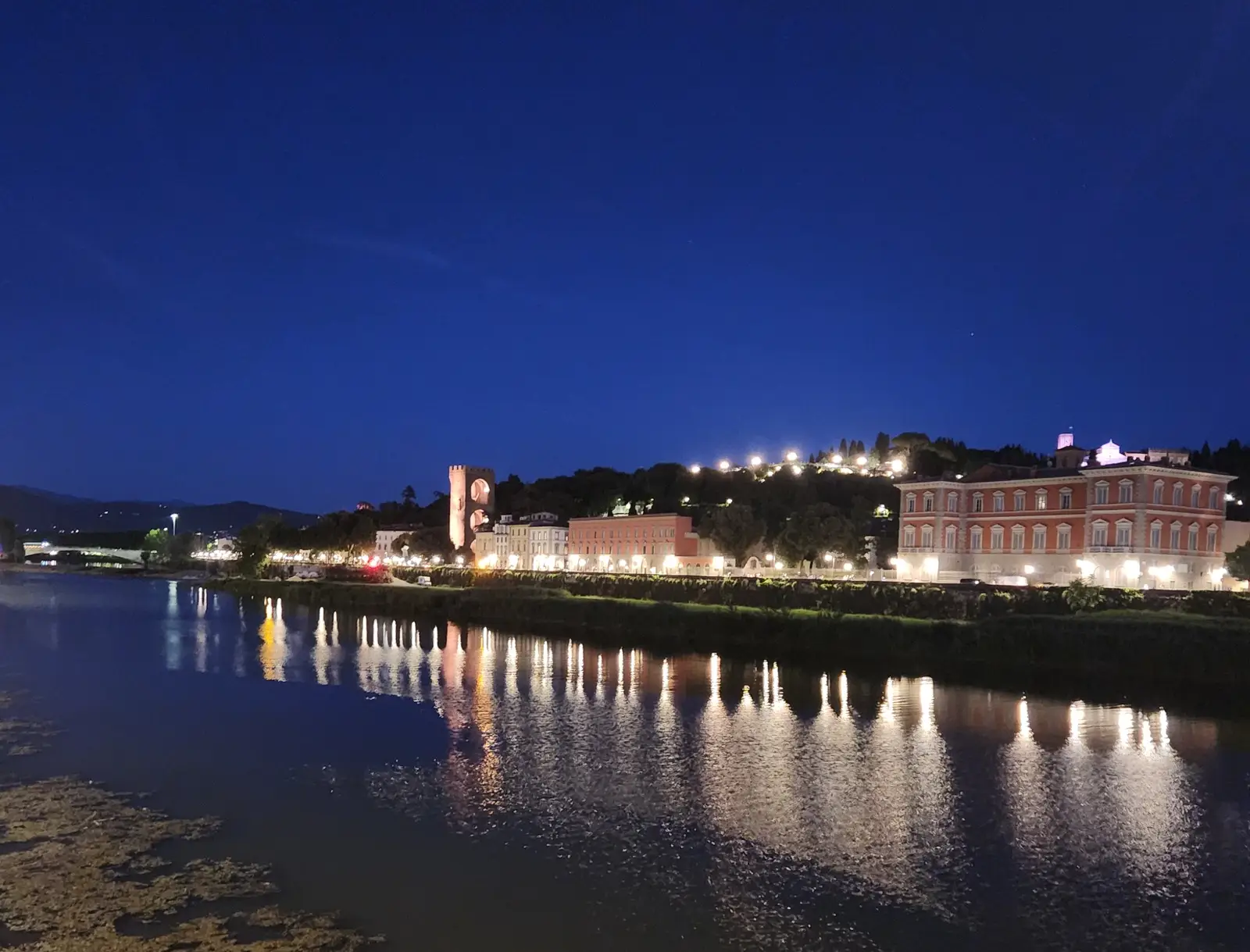 A night view of the Arno River in Florence, Italy, looking toward the Lungarno Serristori area.