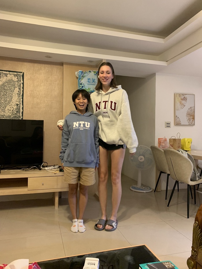 A CET Taiwan student and local roommate posing together while wearing NTU sweatshirts in the living room of their apartment housing