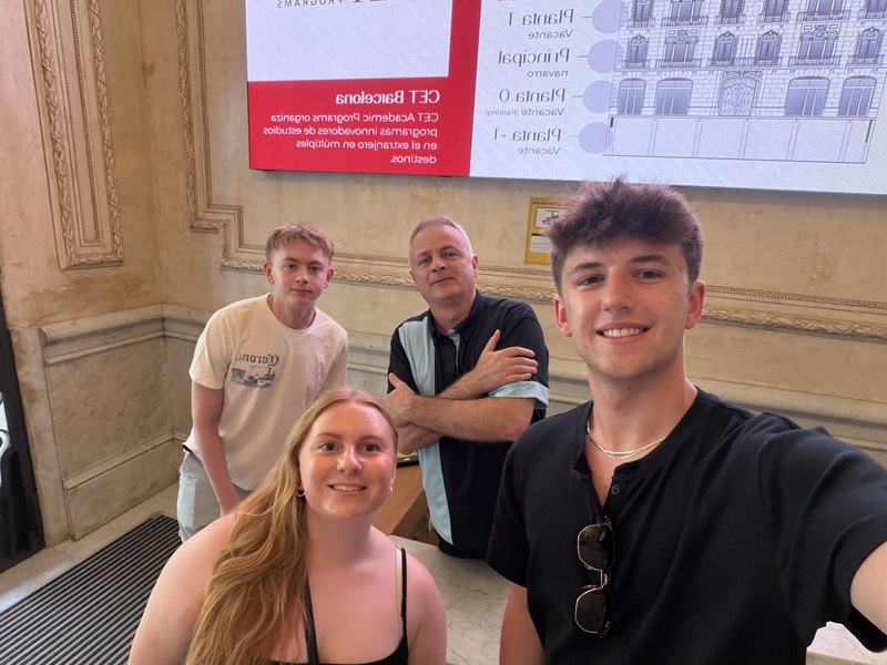 Three CET Barcelona students taking a selfie with a security man at the Barcelona center