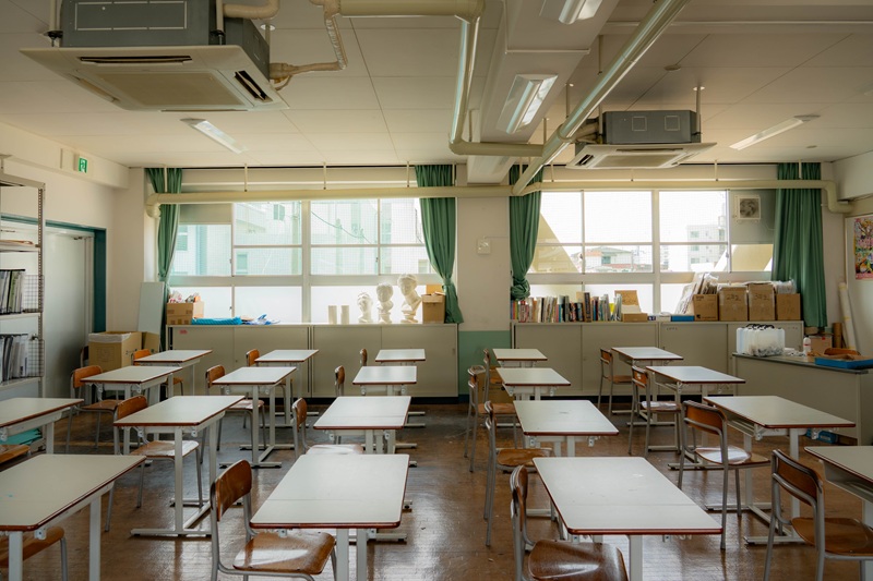 An empty classroom with windows, chairs, and desks
