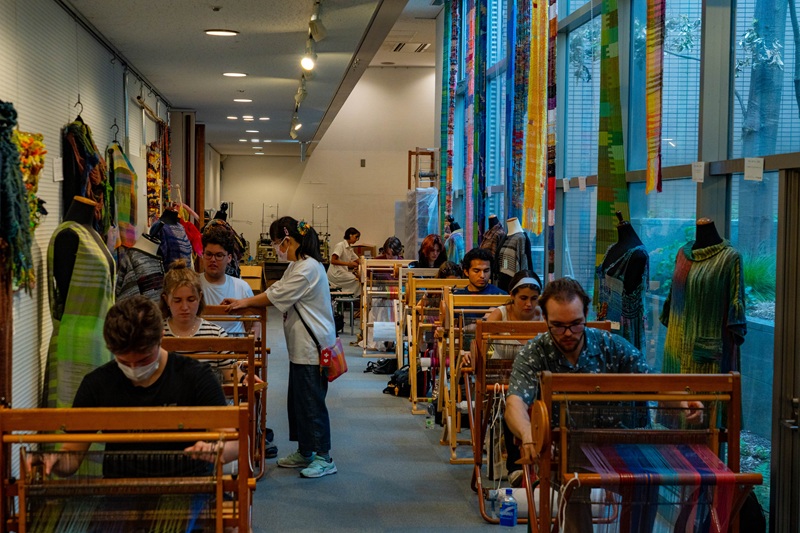 A group of CET students weaving their cloth pieces in a workshop