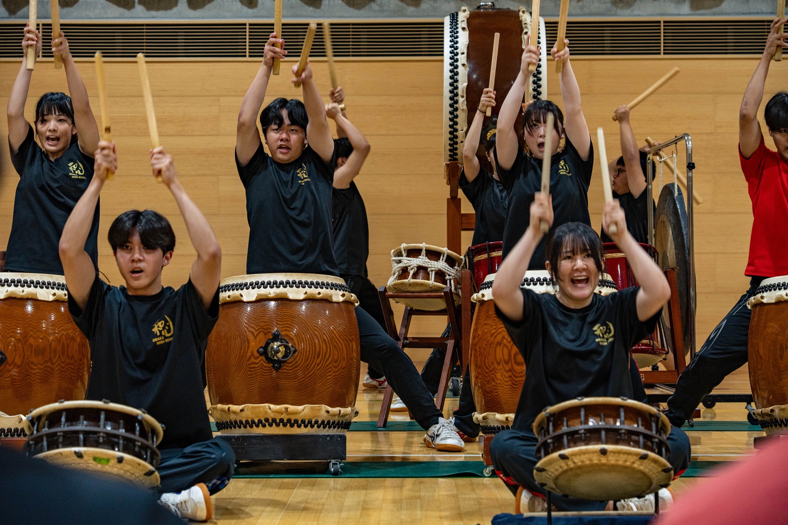 A group of local Japanese high school students raising their sticks while playing Wadaiko, traditional Japanese drumming