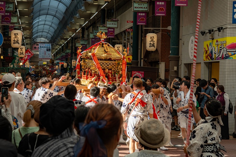 Festival participants carrying a mikoshi through Tenjinbashisuji Shopping Street