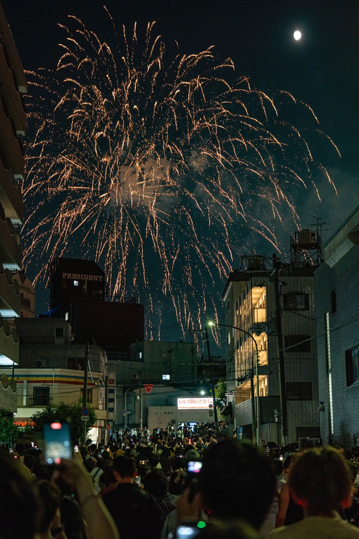 Fireworks above people and buildings in Japan for the Tenjin Matsuri celebration
