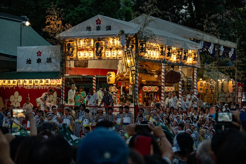 A large crowd of people at Tenmangu Shrine watching performances