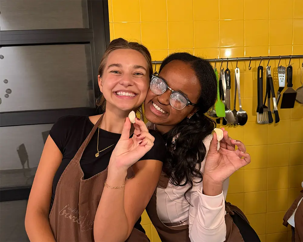 students holding pasta smiling at camera