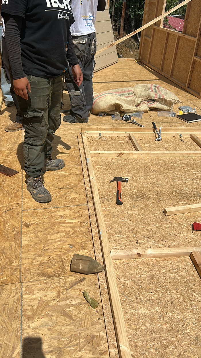 Volunteers working on a wooden house frame.