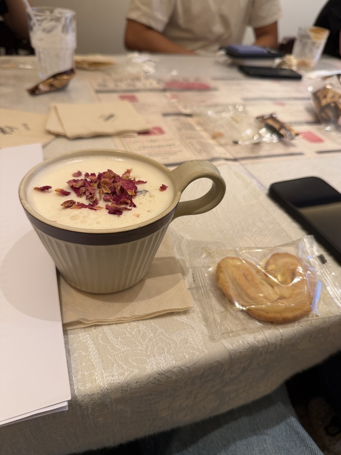 Cup topped with dried rose petals beside a pastry