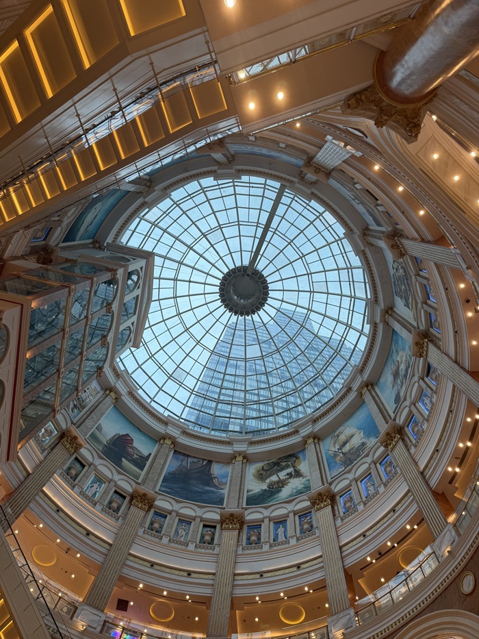 Ornate glass dome and murals inside a building