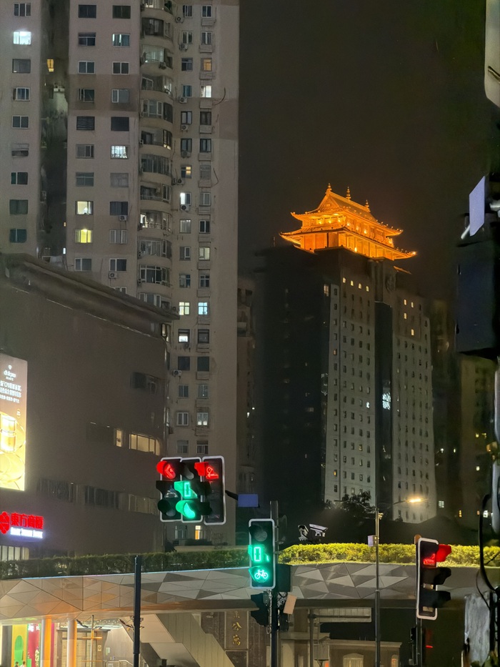 Illuminated traditional rooftop among city buildings at night
