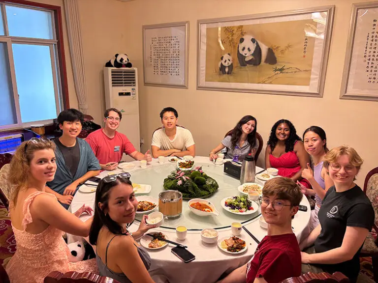 group of students sitting at table smiling at camera
