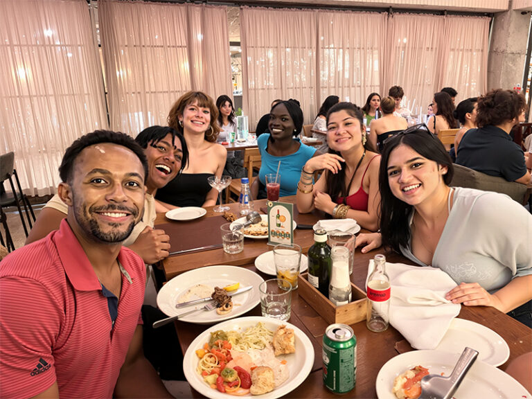 group of students smiling at camera at dinner table